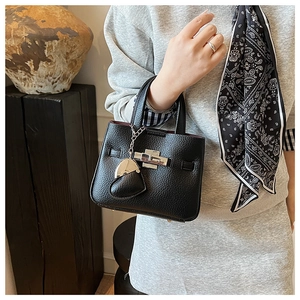 Detail of black lychee grain leather mini bucket bag with silver lock and heart charm