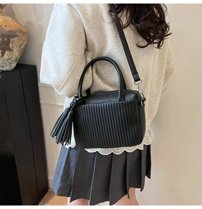 Détail du sac bandoulière noir plissé avec textures verticales et gland latéral