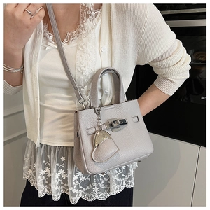 Detail of grey lychee leather bucket bag with silver turn-lock and heart charm