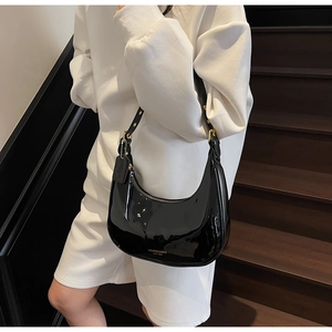 Detail of black patent leather hobo bag featuring gold hardware and side leather tag