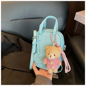 Detail of light blue lychee pattern leather crossbody bag with cute plush bear charm