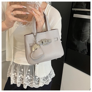 Detail of grey lychee leather bucket bag with silver turn-lock and heart charm