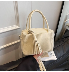 Détail du sac oreiller plissé crème avec texture cuir et pompon décoratif chic