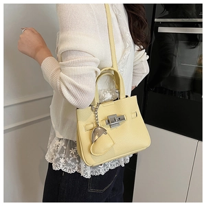 Detail view of bright yellow litchi grain leather bucket bag with silver square twist lock