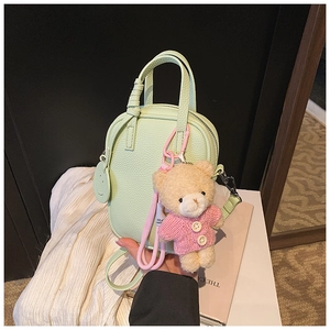 Close-up of mint green lychee texture phone bag with a cute teddy bear plush charm