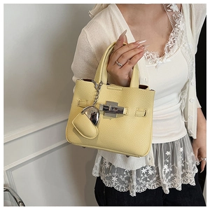 Detailed texture of yellow lychee grain leather handbag with silver lock and heart charm