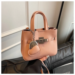 Detail of pink lychee leather bucket bag with silver square lock and heart charm