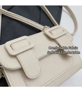Détail macro de la texture cuir grainé et des boucles sur le petit sac bandoulière crème