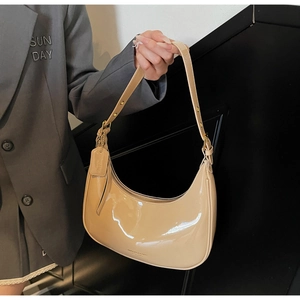 Detail of minimalist beige patent leather hobo bag with adjustable strap and metallic sheen