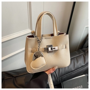 Close-up of litchi pattern beige leather bucket bag with silver lock and heart pendant