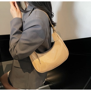 Detail of glossy beige patent leather hobo bag showing sleek crescent shape and strap