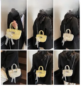Detail view of mini litchi texture handbags in yellow and white with lace and pearl handle