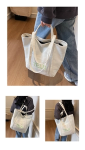 Detail showing high-capacity canvas tote bag with green TELN embroidery and dual straps