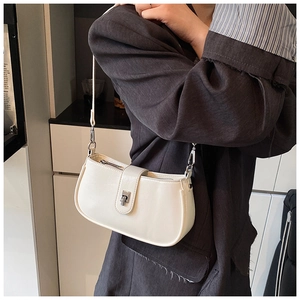 Detail of minimalist cream oil-wax leather baguette bag worn with a gray suit blazer