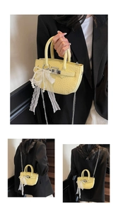 Detail view of yellow leather bucket bag with pearl lace bow charm and silver chain