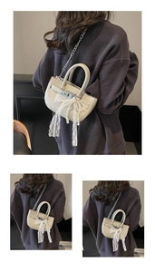 Detail of off-white mini bucket bag featuring lace bow and pearl charm accessories