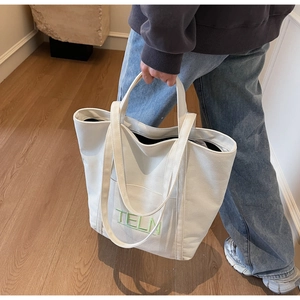 Close-up of cream canvas tote bag with green TELN embroidery and thick durable fabric