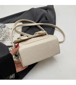 Détail de la texture cuir grainé beige sur un sac à bandoulière carré élégant