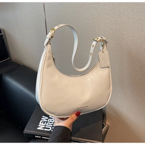Detailed view of white patent leather hobo bag with adjustable strap and gold hardware