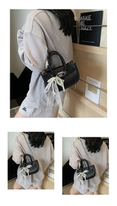 Close-up of black litchi leather bucket bag featuring lace bow charm and chain strap
