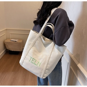 Detail of white canvas tote bag with green TELN embroidery and large capacity for daily use