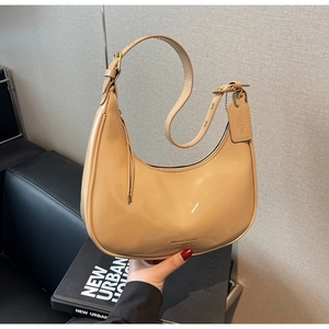 Detailed macro view of beige patent leather shoulder bag with golden hardware accents