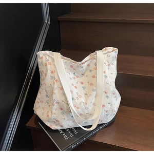 Detailansicht einer floralen Spitze-Tragetasche mit zarten Blumendrucken auf Holzstufen