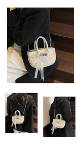 Detail of white lychee leather bucket bag with lace bow and pearl charm on stairs