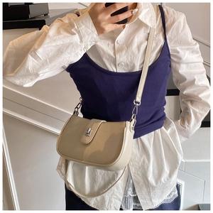 Detailed view of creamy white faux leather shoulder bag with a silver metal turn-lock