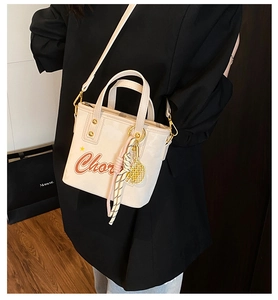 Détail du sac seau blanc avec imprimé lettres et breloque raquette de tennis