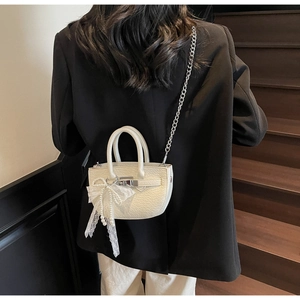Close-up of white pebble leather bucket bag with lace pearl bow and silver chain strap