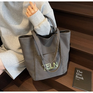 Detailed close-up of dark grey canvas tote bag with neon green letter embroidery