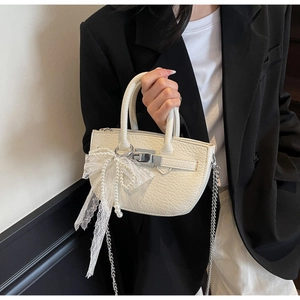 Detail of cream white bucket bag with lace bow, pearls, and silver chain strap