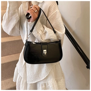 Detail of black faux leather underarm bag with metal buckle on a white dress