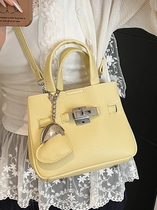 Minimalist pale yellow lychee pattern leather bucket bag with silver twist lock and heart charm