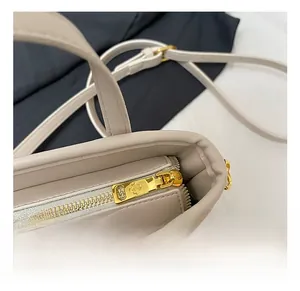 Gros plan sur le logo trèfle du zip et la texture fine du sac seau beige