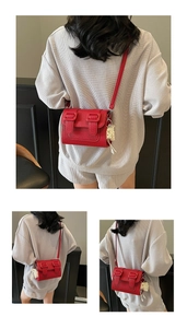 Detail of red lychee pattern crossbody bag with pearl tassel and buckle straps