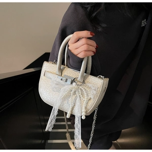 Close-up of cream bucket bag with silver twist lock and lace pearl accessories