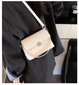 Close-up of beige oil wax leather crossbody bag with silver round metal buckle closure