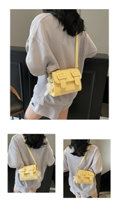 Detail of yellow pebbled leather crossbody bag with decorative pearl and lace pendant