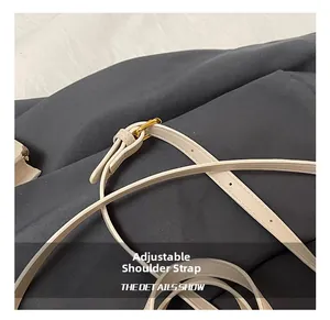 Détail de la bandoulière réglable en cuir crème avec boucle dorée et surpiqûres précises