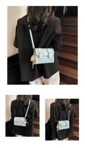Detail view of mint blue satchel with double buckles and a pearl tassel pendant