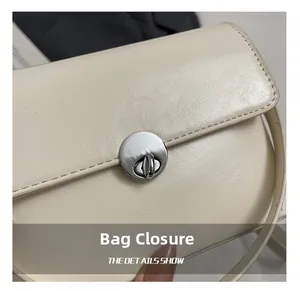 Detailed macro view of the silver metallic circular twist lock on creamy faux leather bag