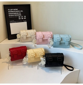 Showcase of six colorful crossbody square bags with pearl lace charms on pedestals