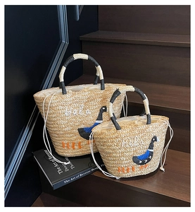 Detail of woven straw beach bags with bird embroidery and drawstring lining on stairs
