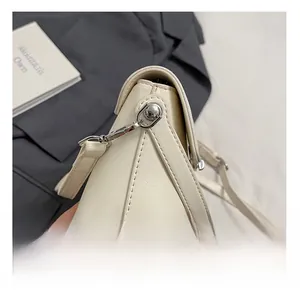 Detail view showing clean stitching and silver hardware on a cream leather crossbody bag