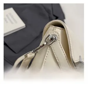Detailed macro view of the silver metal hardware buckle and strap joint on white leather bag