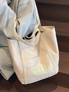 Beige canvas tote bag with green TELN embroidery, featuring shoulder straps and top handles