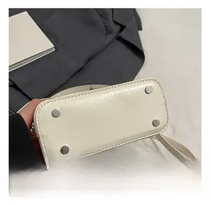 Detail view of cream white leather bag bottom featuring four protective metal studs