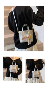 Détail du sac seau métallisé argenté avec imprimé artistique et pendentif à gland